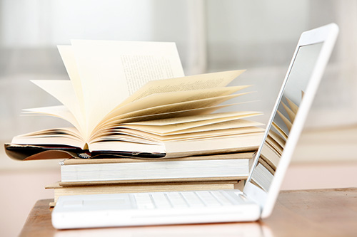 Stack of books next to an open laptop Stack of books next to an open laptop
