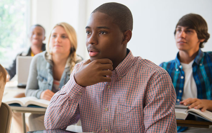 High school students in class listening with interest to a teacher High school students in class listening with interest to a teacher