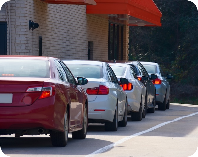 Cars lined up in a fast food drive through.