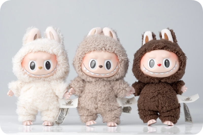 Three Labubu dolls, one white, one light brown, and one dark brown