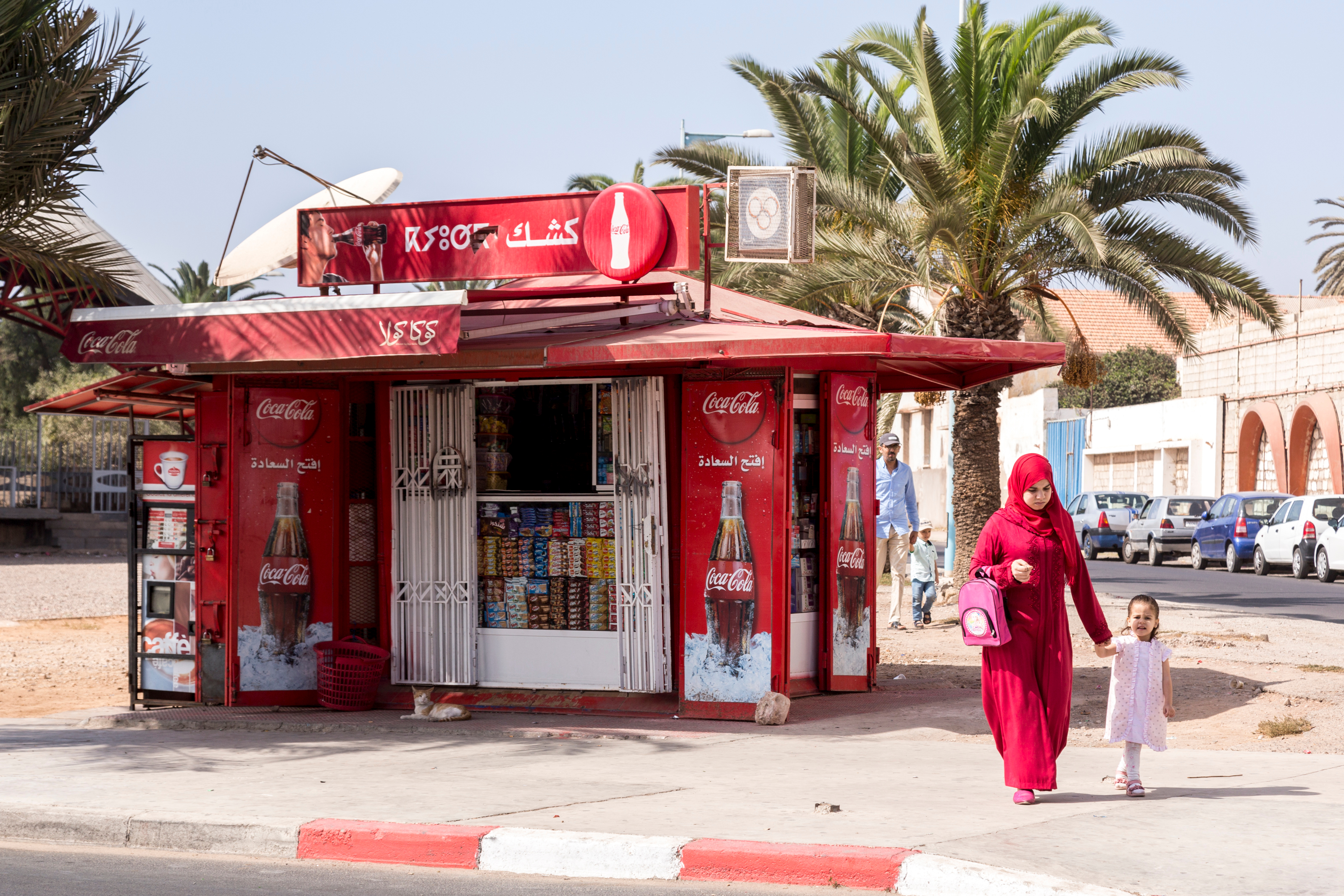 Agadir, Morocco, October 23, 2017: Muslim mother in red hijab walks past red Coca Cola kiosk.; Shutterstock ID 768122374; PO: Arens_ContempAdver, 16e; Job: 1260259307; Client: Ann Marie Jannette