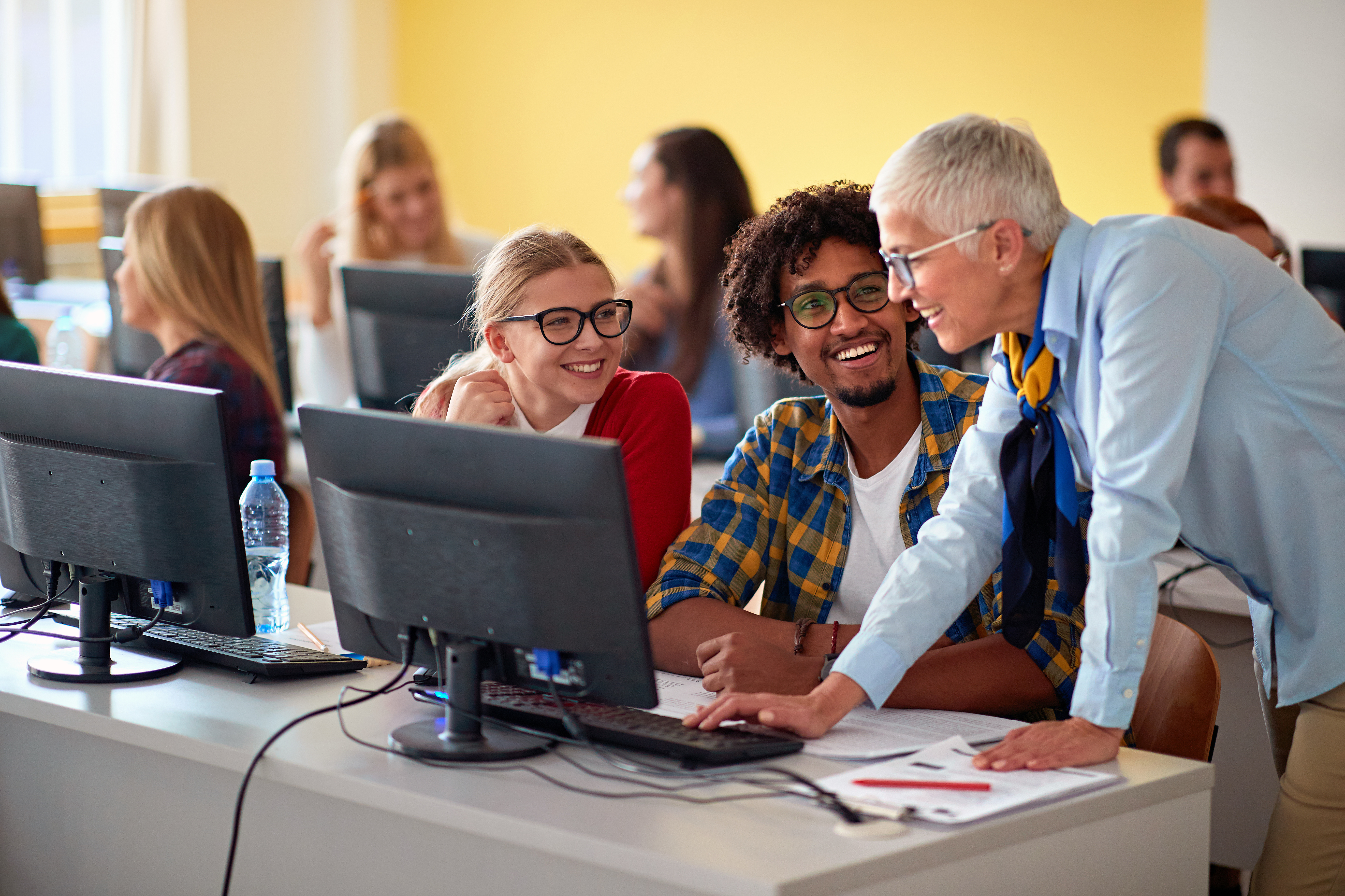 Woman lecturer in computer class assisting group of student on campus