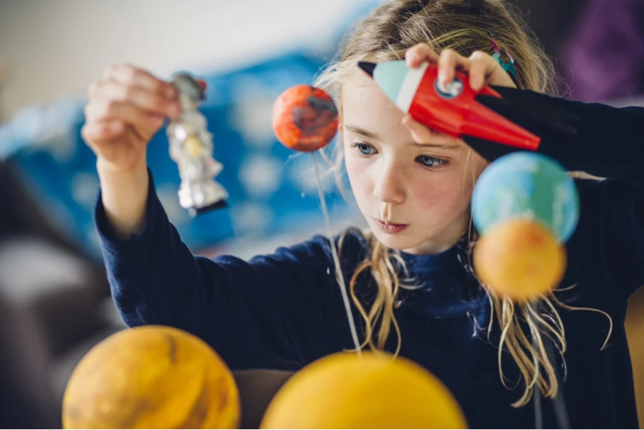 young girl playing with solar system toys
