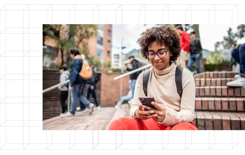 Young student sitting
on steps looking at phone.