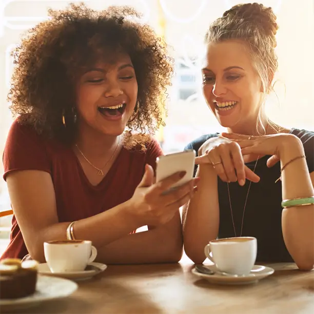 two women having coffee and looking at cellphone