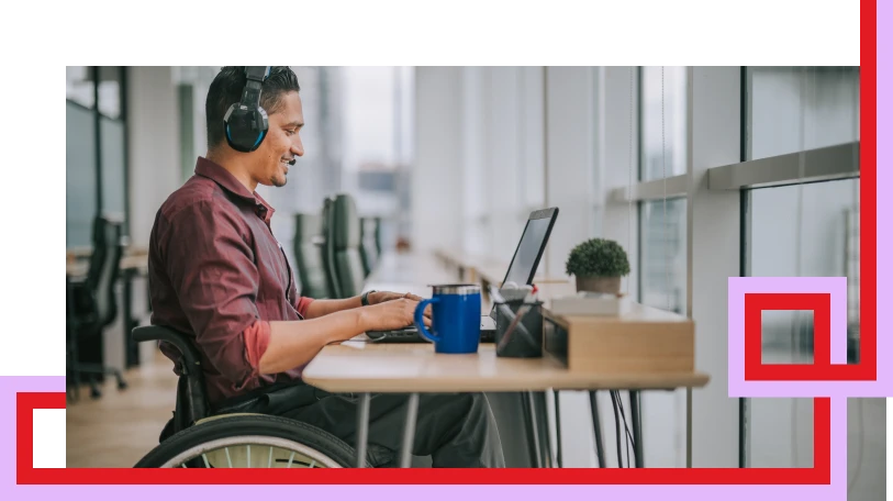 Male in a wheel chair typing on a laptop at a desk.