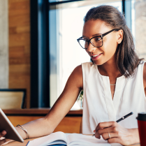 Woman wearing glasses and writing in book 