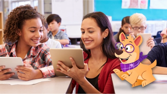 Elementary school students in classroom with teacher working on device next to student