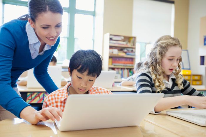 Two elementary students getting help from social studies teacher