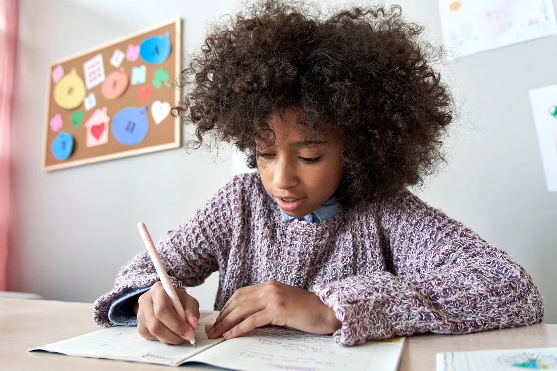 student sitting at desk writing in workbook