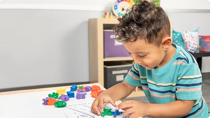 A child smiles as he plays with colorful plastic toys.